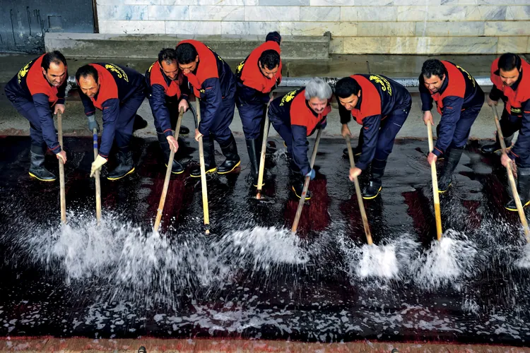 水をかけながらブラシでギャッベを洗う人たち